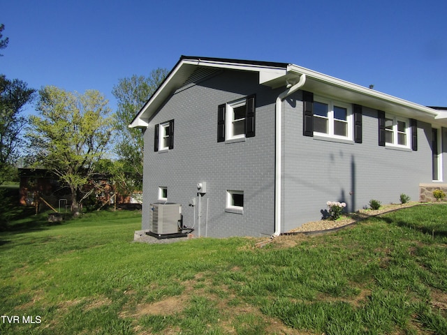 view of home's exterior featuring cooling unit, brick siding, and a lawn