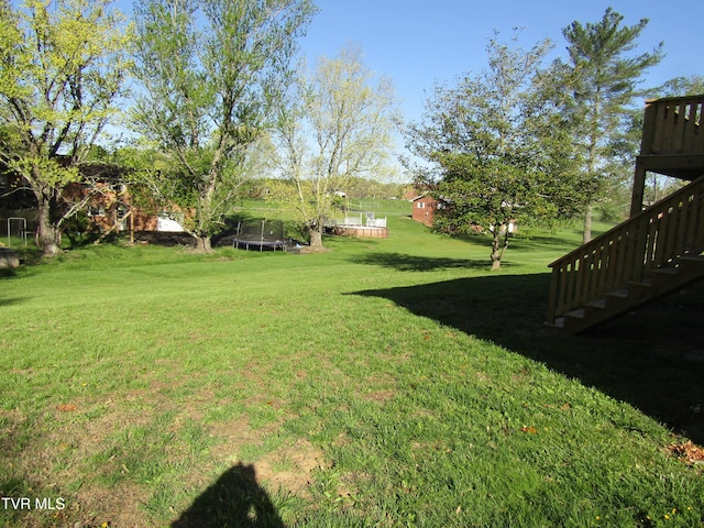view of yard with a trampoline and stairs