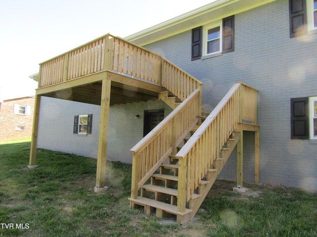 back of house featuring brick siding, a wooden deck, a yard, and stairs