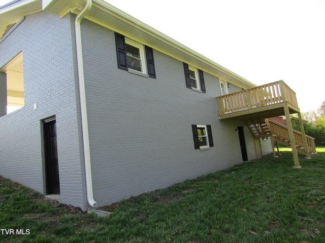view of side of property featuring brick siding, a yard, a wooden deck, and stairway