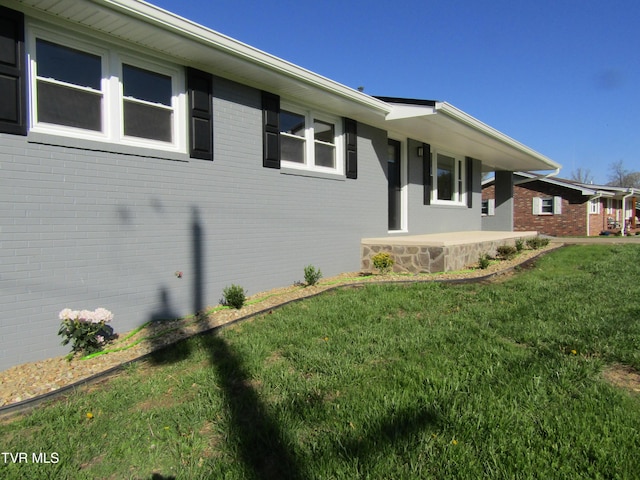 view of property exterior with brick siding and a lawn