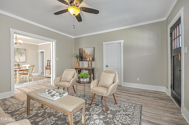 sitting room with wood-type flooring, ornamental molding, and ceiling fan with notable chandelier