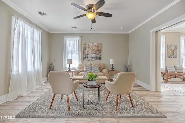 living room with crown molding, light hardwood / wood-style flooring, and ceiling fan