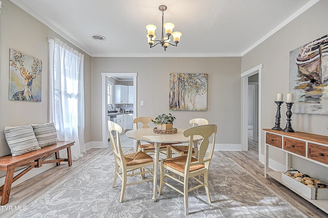 dining space featuring a notable chandelier, crown molding, and light wood-type flooring