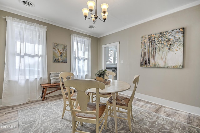 dining room with ornamental molding, hardwood / wood-style floors, and an inviting chandelier