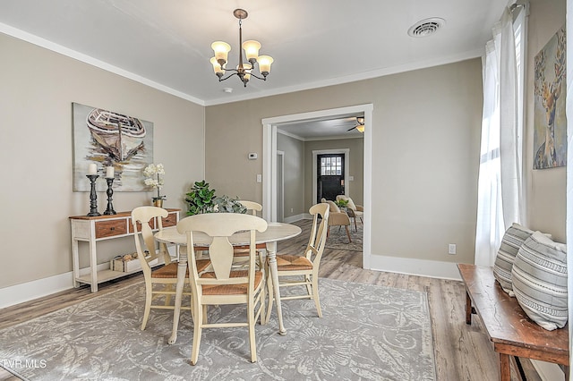 dining room featuring crown molding, wood-type flooring, and ceiling fan with notable chandelier