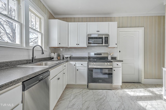 kitchen featuring tasteful backsplash, white cabinetry, appliances with stainless steel finishes, and sink