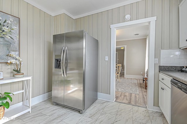 kitchen featuring tasteful backsplash, ornamental molding, stainless steel appliances, and white cabinets