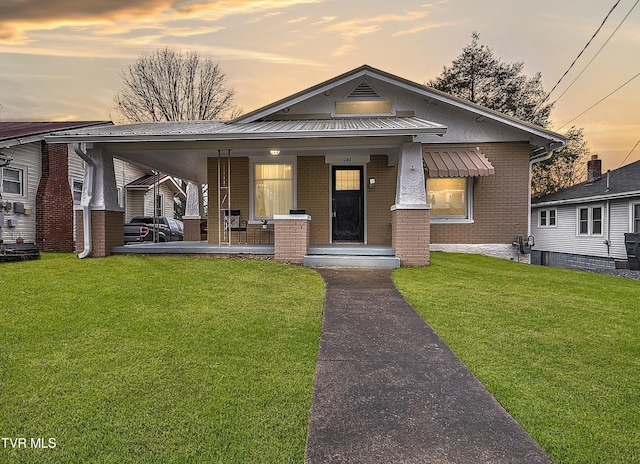 bungalow-style house with covered porch and a lawn