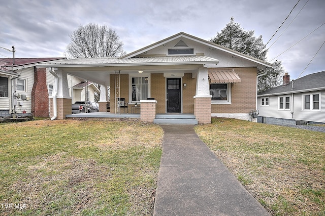 bungalow with covered porch and a front lawn