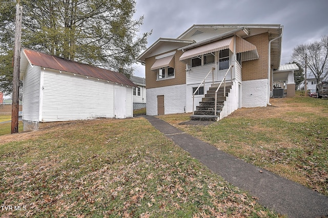 view of front facade with central AC, an outdoor structure, and a front yard