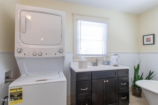 laundry room with stacked washer / drying machine, sink, and light tile patterned flooring