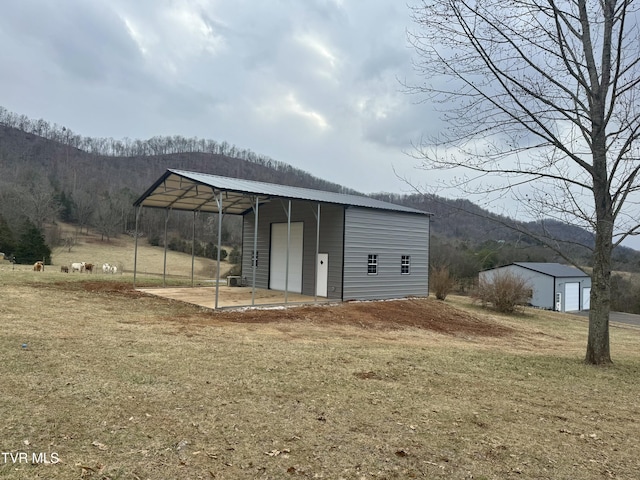 view of outdoor structure featuring a yard, a garage, a mountain view, and a carport