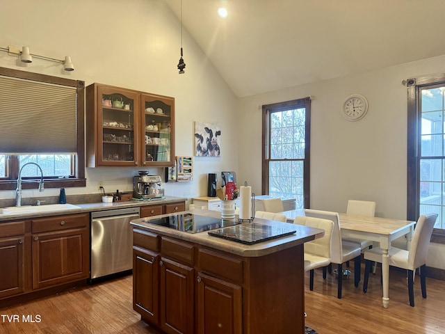 kitchen featuring vaulted ceiling, a kitchen island, dishwasher, sink, and light hardwood / wood-style floors