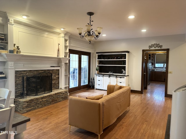 living room with wood-type flooring, a chandelier, and a fireplace