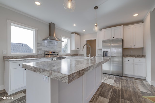 kitchen featuring a kitchen island, pendant lighting, white cabinets, stainless steel appliances, and wall chimney exhaust hood