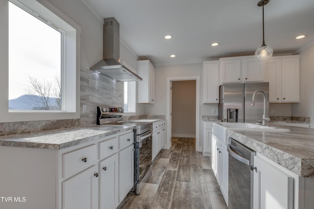 kitchen featuring white cabinetry, wall chimney range hood, pendant lighting, and appliances with stainless steel finishes