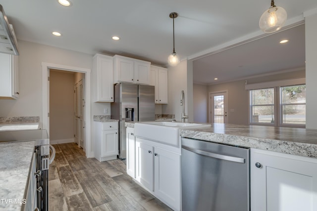 kitchen with sink, hanging light fixtures, stainless steel appliances, white cabinets, and light wood-type flooring