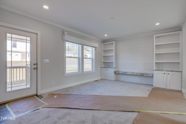 unfurnished living room featuring ornamental molding and light colored carpet