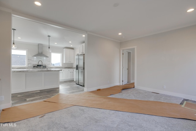 kitchen with pendant lighting, white cabinetry, stainless steel fridge with ice dispenser, light colored carpet, and wall chimney exhaust hood