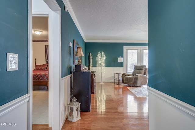 hallway with crown molding, hardwood / wood-style floors, and a textured ceiling