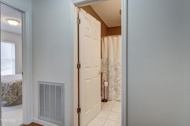 corridor with light tile patterned floors and a textured ceiling