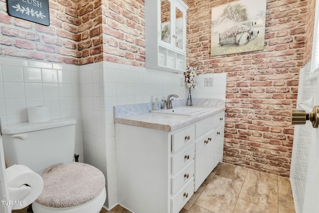 bathroom featuring brick wall, toilet, and vanity