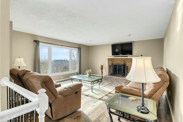 living room featuring hardwood / wood-style flooring, a brick fireplace, and a textured ceiling