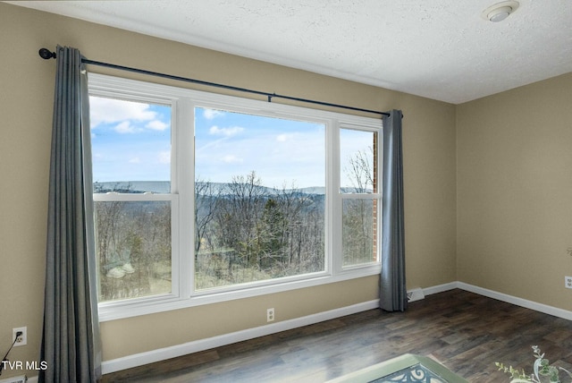 spare room featuring dark hardwood / wood-style flooring and a textured ceiling