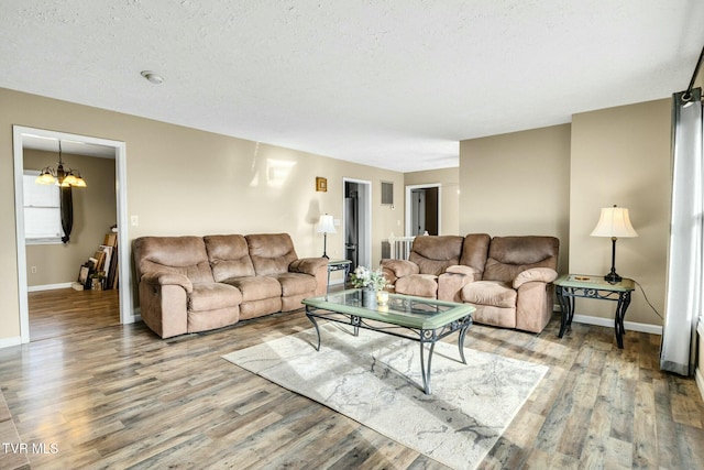 living room featuring hardwood / wood-style flooring, a textured ceiling, and a chandelier