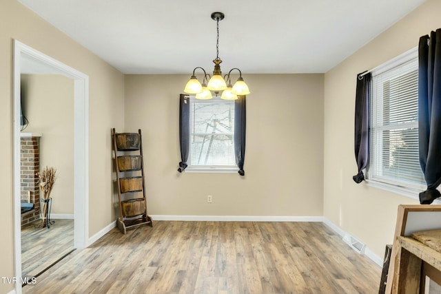 unfurnished room with light hardwood / wood-style floors and a notable chandelier