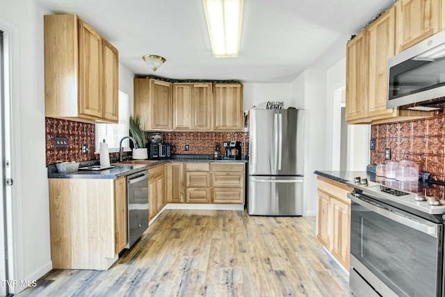 kitchen featuring tasteful backsplash, appliances with stainless steel finishes, sink, and light wood-type flooring