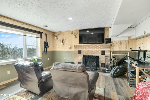 living room with wood-type flooring, a fireplace, and a textured ceiling