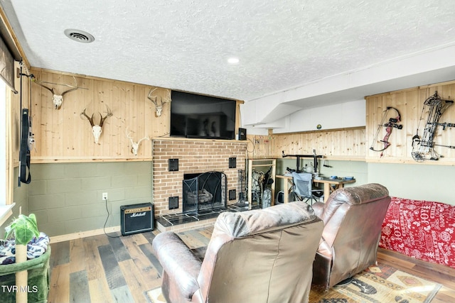 living room featuring hardwood / wood-style flooring, a fireplace, and a textured ceiling