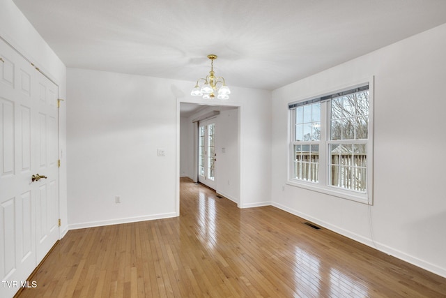 spare room with a notable chandelier and hardwood / wood-style flooring