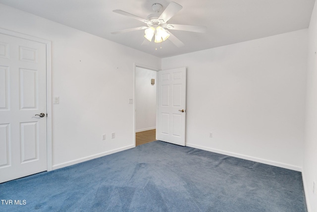 spare room with dark carpet and ceiling fan