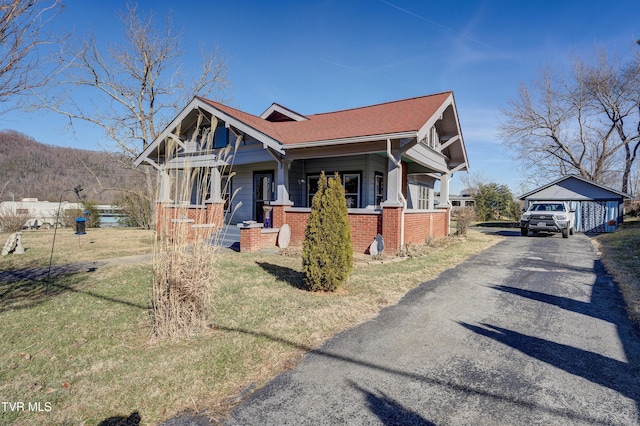 craftsman-style home featuring a garage, an outdoor structure, a front lawn, and a porch