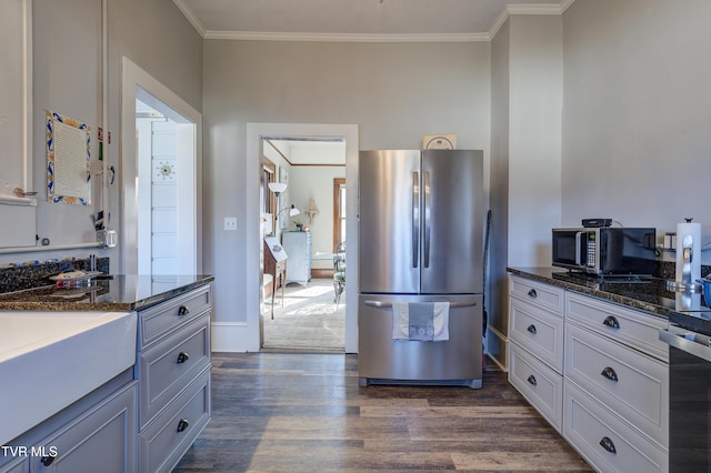 kitchen with dark hardwood / wood-style flooring, crown molding, stainless steel refrigerator, and dark stone countertops