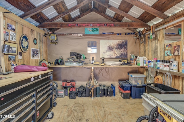 misc room featuring lofted ceiling with beams, a workshop area, and wood walls