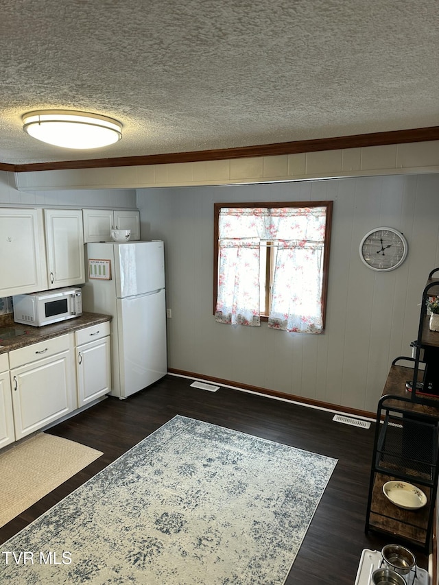 kitchen with dark hardwood / wood-style flooring, white appliances, a textured ceiling, and white cabinets