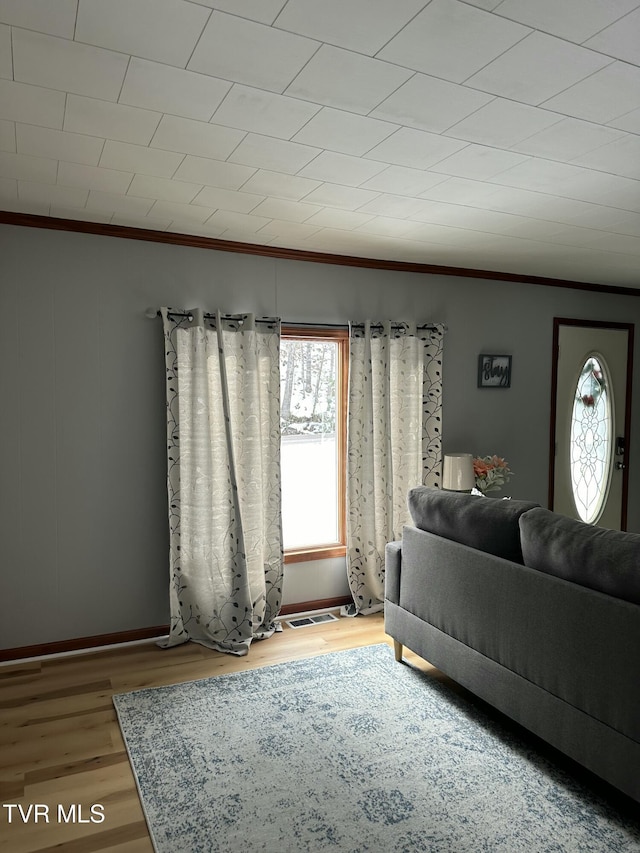 unfurnished living room featuring crown molding and wood-type flooring