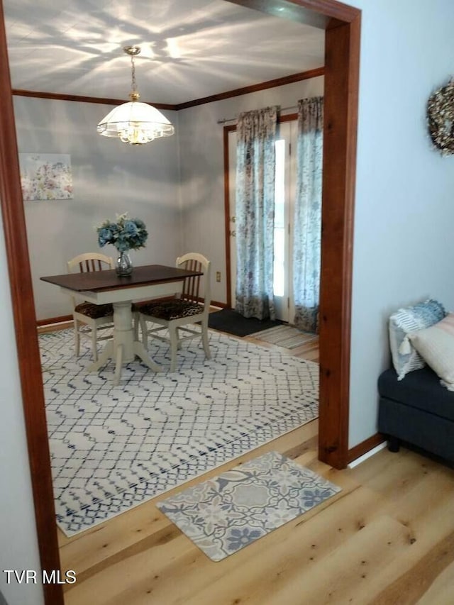 dining space featuring an inviting chandelier, ornamental molding, and hardwood / wood-style floors