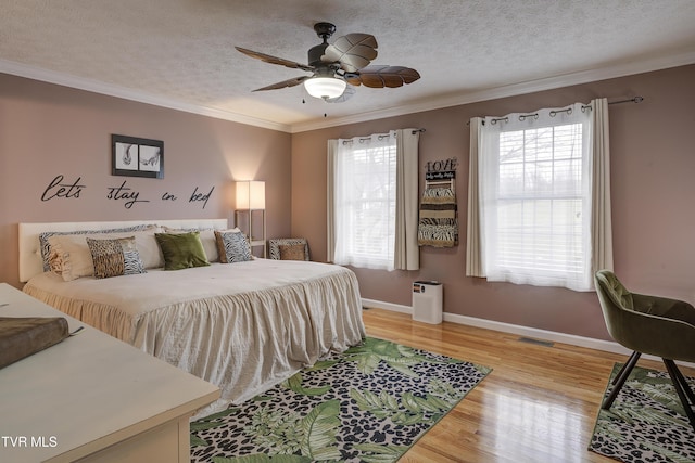 bedroom featuring hardwood / wood-style flooring, ceiling fan, multiple windows, and a textured ceiling