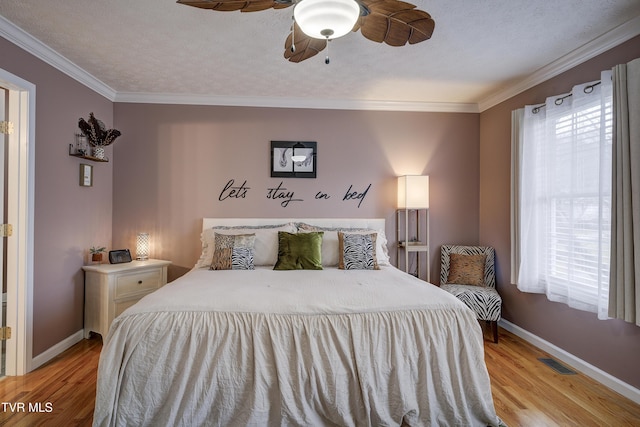 bedroom featuring a textured ceiling, light hardwood / wood-style flooring, ornamental molding, and ceiling fan