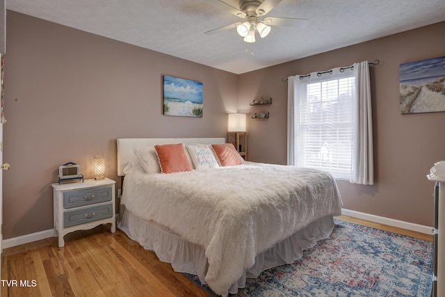 bedroom featuring light wood-type flooring, a textured ceiling, and ceiling fan