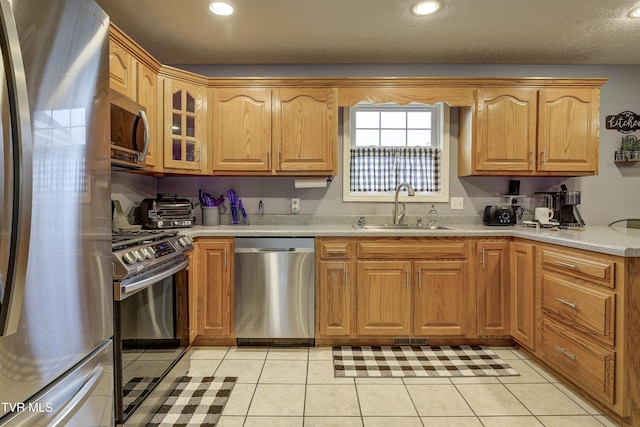 kitchen featuring light stone counters, sink, light tile patterned floors, and appliances with stainless steel finishes