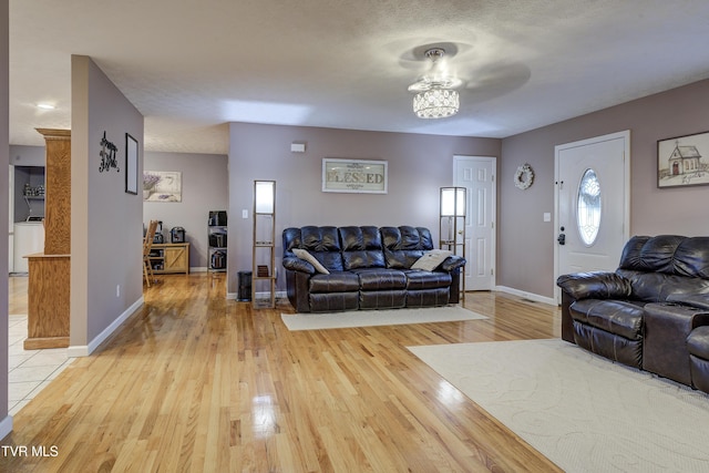 living room featuring washer / dryer, light hardwood / wood-style flooring, and a textured ceiling