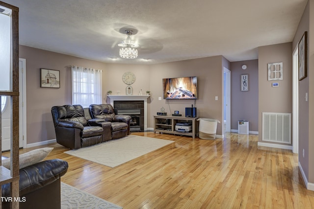 living room with a tiled fireplace, hardwood / wood-style floors, and a textured ceiling