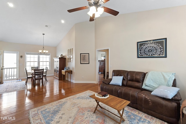 living room with wood-type flooring, ceiling fan with notable chandelier, and high vaulted ceiling