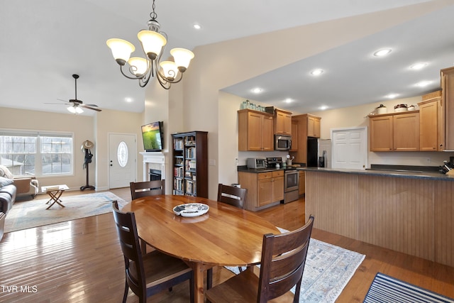 dining space featuring high vaulted ceiling, ceiling fan with notable chandelier, and light hardwood / wood-style floors